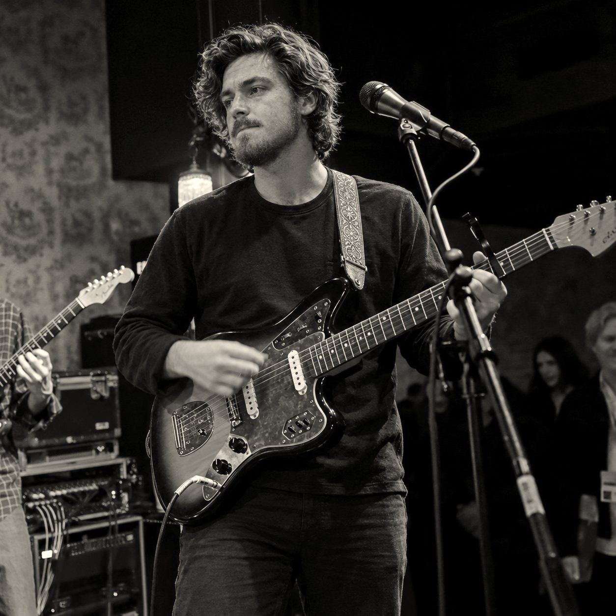 Adam Cole singing and playing guitar on stage